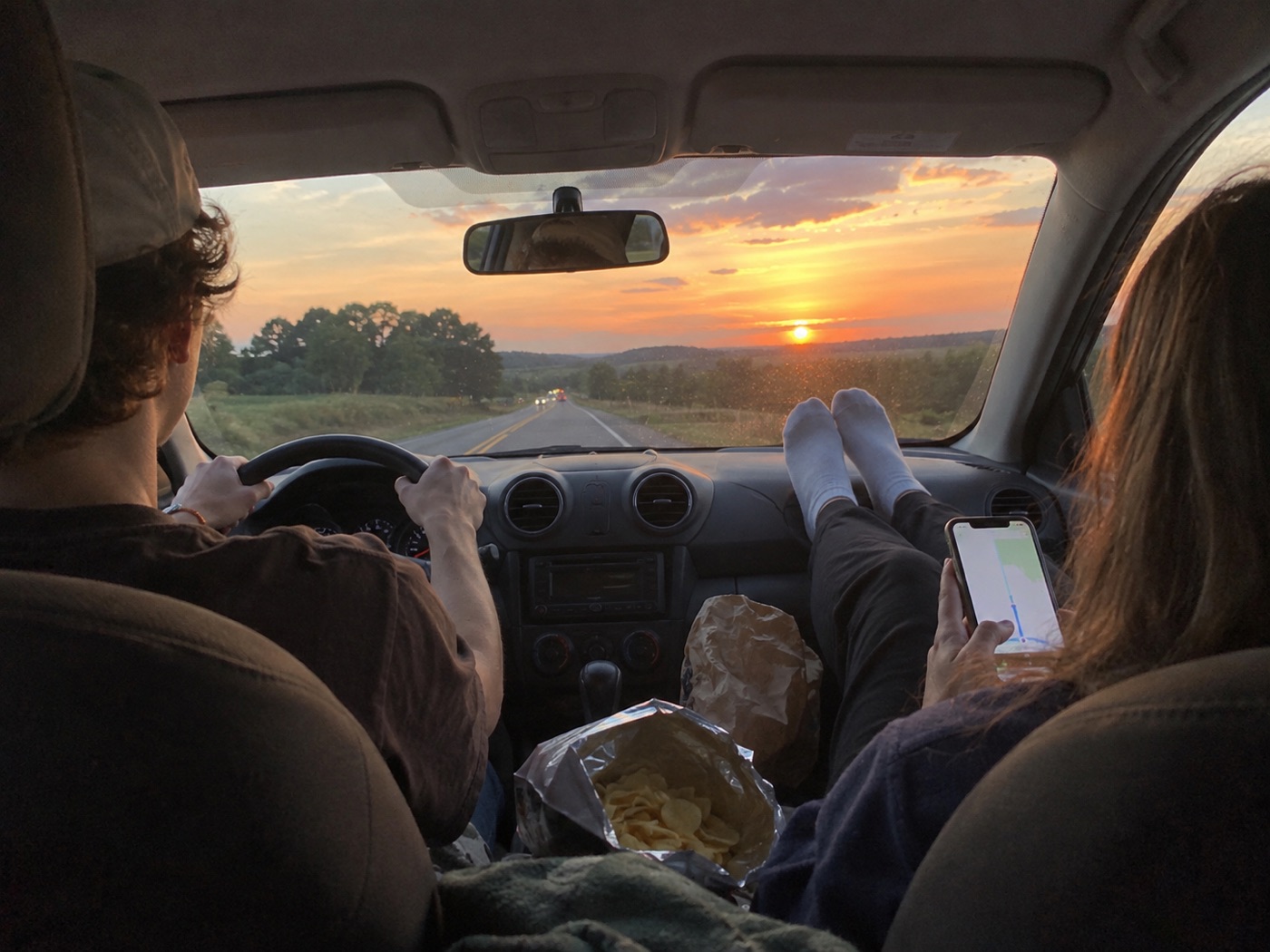 The back seat of a car on a sunset road trip
